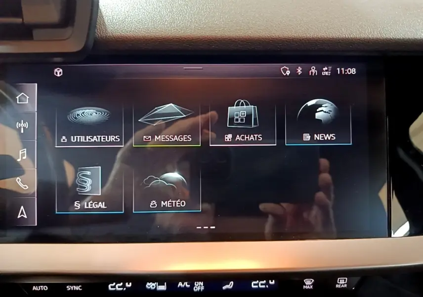 Écran tactile central de l’Audi A3 gris foncé, affichant le menu principal avec options messages et météo.