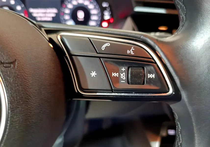 Gros plan sur le côté gauche du volant cuir d'une Audi A3 35 TFSI 150 MHEV avec commandes multifonctions.