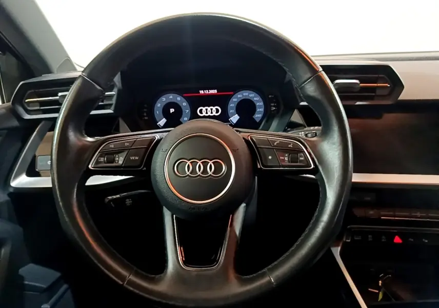Vue centrée sur le volant cuir noir et le tableau de bord numérique de l'Audi A3 gris foncé, version 2021.