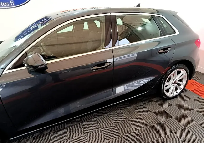 Vue de profil côté gauche d'une Audi A3 gris foncé 35 TFSI 150 MHEV avec jantes alliage et rétroviseurs noirs.