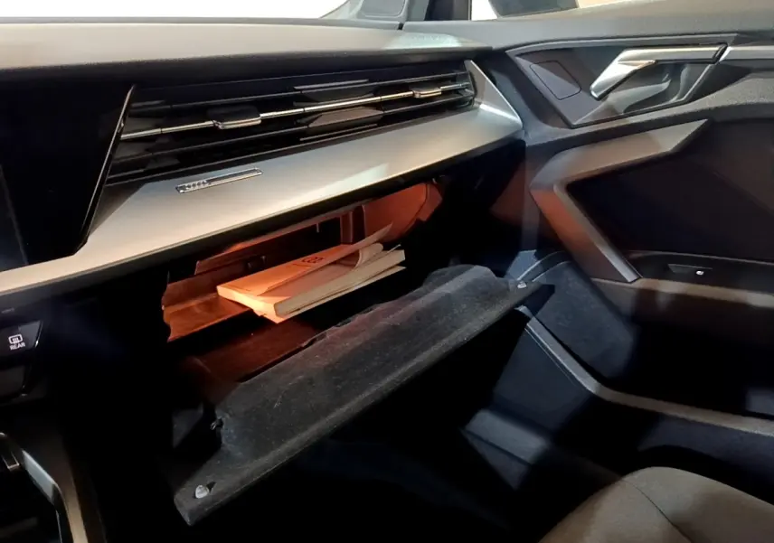 Intérieur côté passager d’Audi A3 gris foncé 2021, boîte à gants ouverte avec documents visibles.