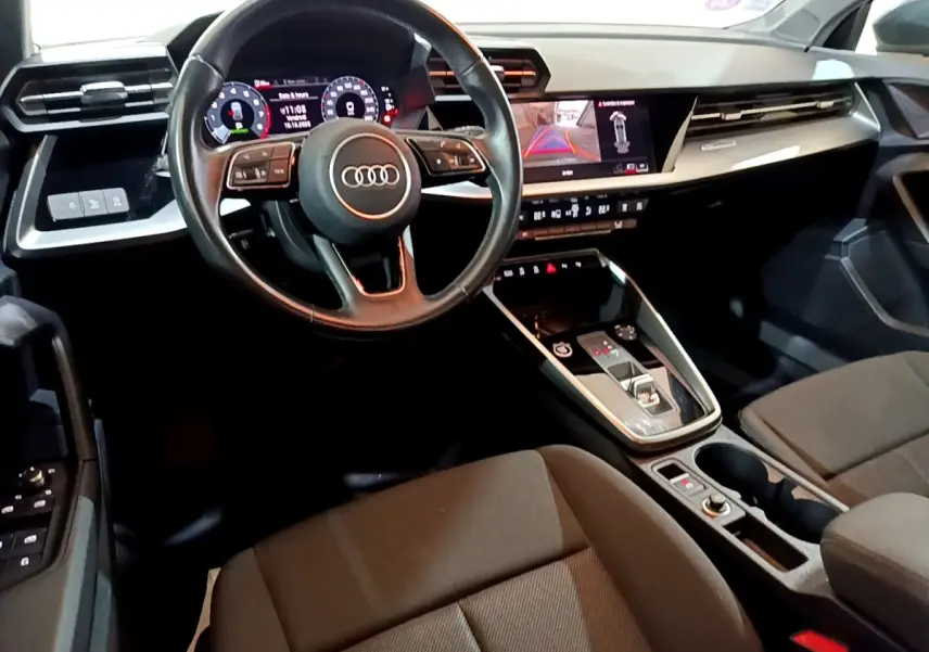Vue intérieure côté conducteur de l'Audi A3 35 TFSI 150 MHEV avec volant cuir multifonctions et écran tactile.