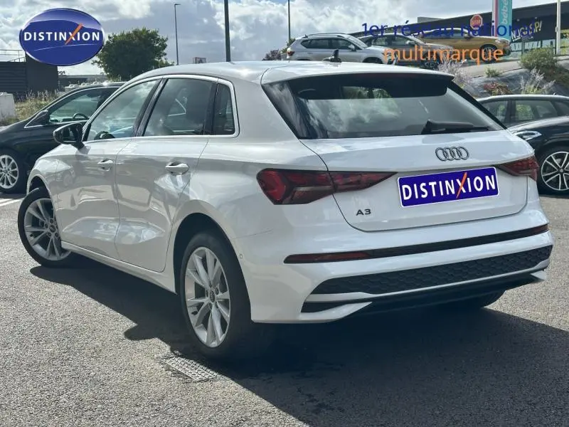 Audi A3 Sportback blanche vue en 3/4 arrière droit, avec feux arrière LED et jantes alliage visibles.