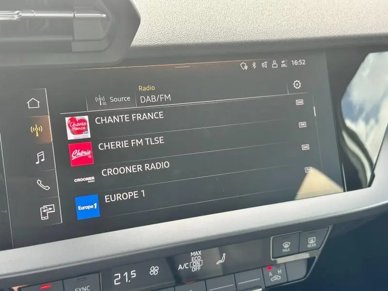 Écran tactile central de l'Audi A3 Sportback 2024 affichant les stations radio DAB/FM, vue intérieure frontale.