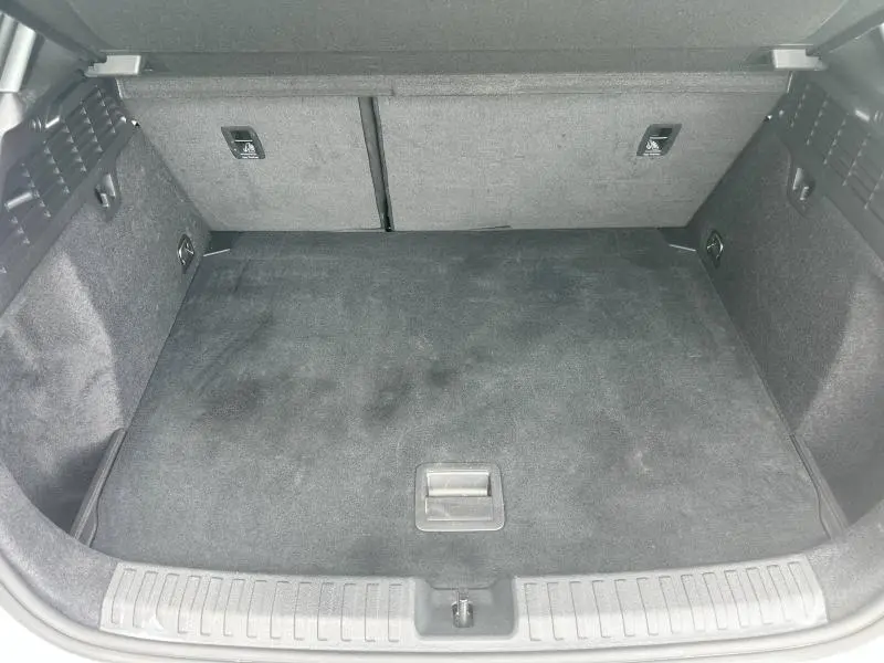 Coffre vide vu de face de l'Audi A3 Sportback 2024, revêtement tissu gris foncé avec cache-bagages déployé.