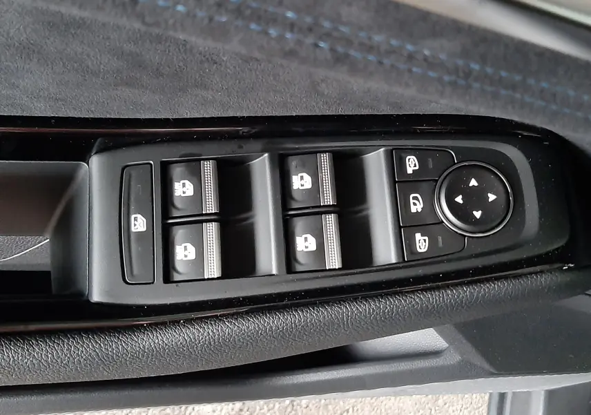 Vue rapprochée des commandes de lève-vitres et rétroviseurs sur la porte côté gauche du Renault Austral gris schiste satin.