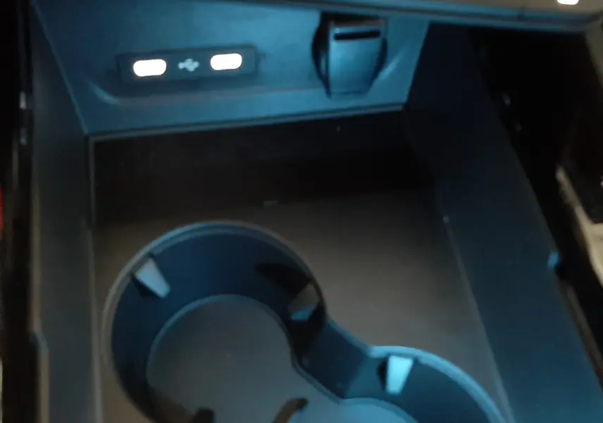Gros plan sur la console centrale du Renault Austral E-Tech 2025, montrant porte-gobelets et ports USB éclairés.