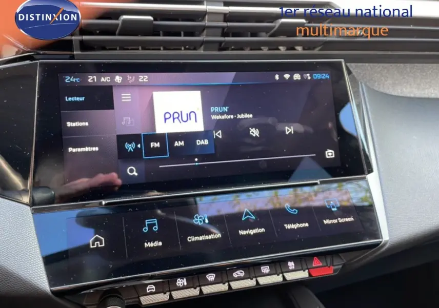 Écran tactile central de la Peugeot 308 2024 montrant l’interface multimédia avec radio FM et commandes climatisation.