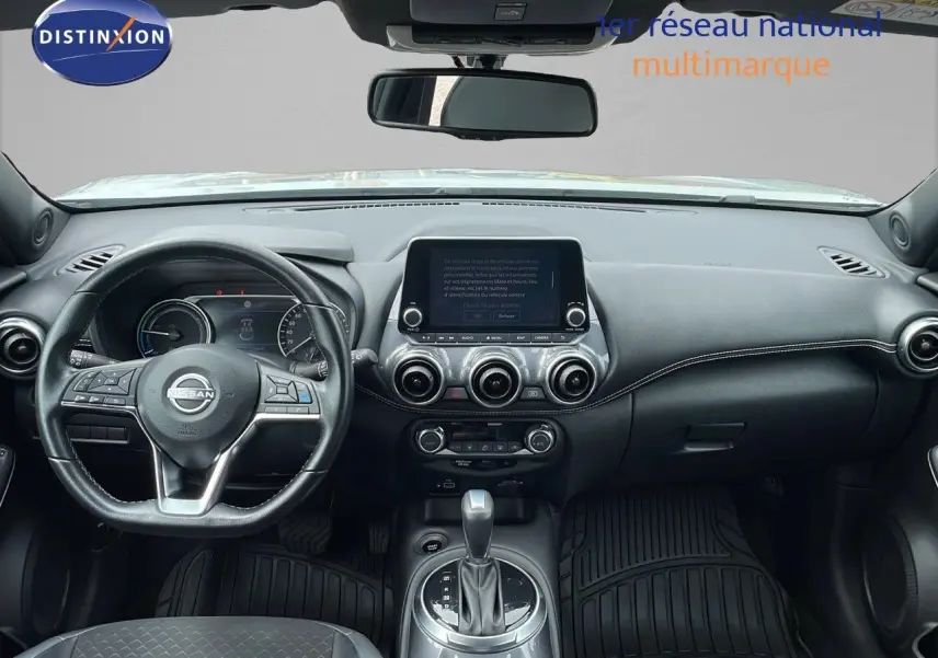 Intérieur noir du Nissan Juke Hybrid 2023 vu de face, tableau de bord moderne avec écran tactile central et volant multifonction.