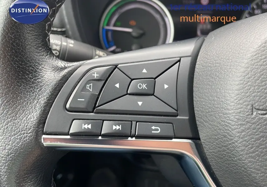 Gros plan sur les commandes à gauche du volant en cuir noir du Nissan Juke hybride 2023, tableau de bord en arrière-plan.