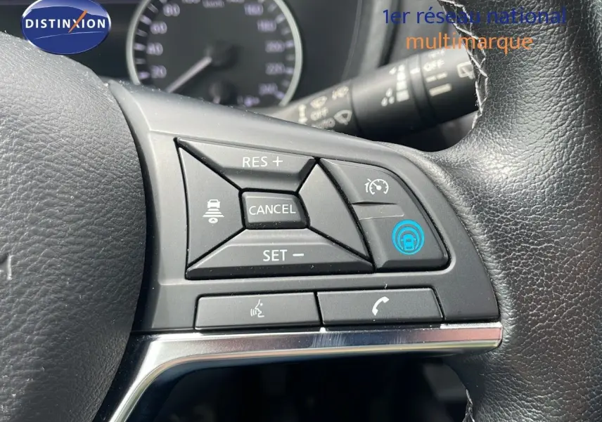 Gros plan sur les commandes de régulateur de vitesse au volant cuir noir du Nissan Juke Hybrid gris perle 2023.