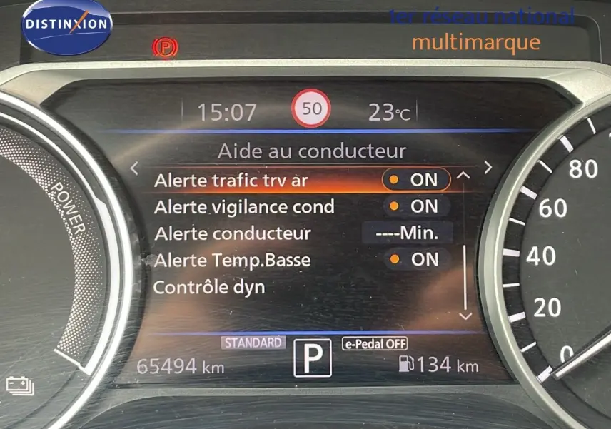 Tableau de bord du Nissan Juke Hybrid 2023 affichant les alertes conducteur et la vitesse, vue intérieure frontale.