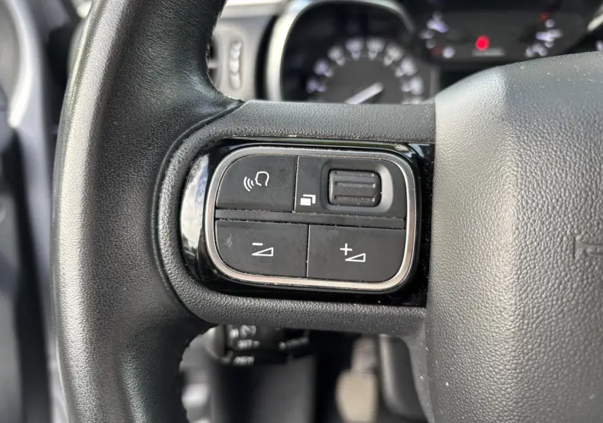 Gros plan sur les commandes audio au volant de la Citroën C3 2019, finition Feel Business, en intérieur noir.