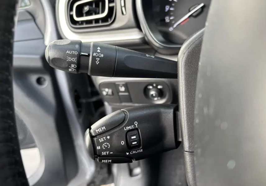 Gros plan sur les commandes au volant de la Citroën C3 2019, avec réglages du régulateur et des feux visibles.