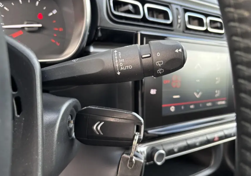 Gros plan sur la commande d'essuie-glace et clé insérée dans le contacteur d'une Citroën C3 2019, intérieur noir.