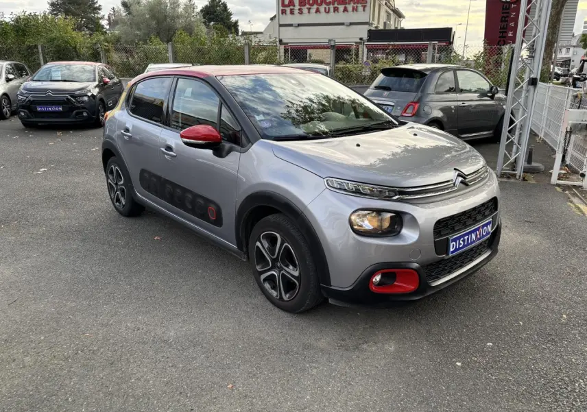 Citroën C3 gris à toit rouge en 3/4 avant droit, avec Airbump noir et accents rouges sur pare-chocs et rétroviseur.