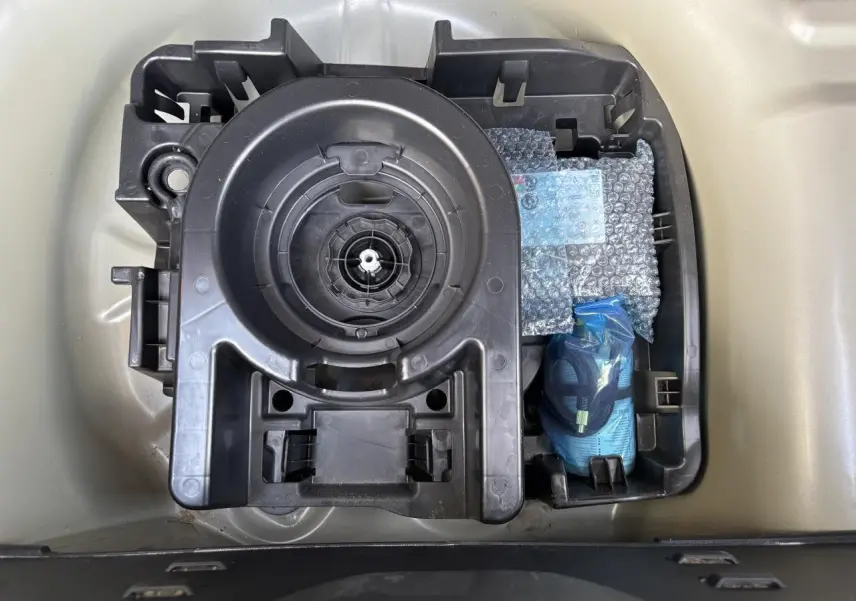 Vue de dessus du compartiment de rangement sous le coffre d'une Citroën C3 gris avec kit de réparation pneus et outils.