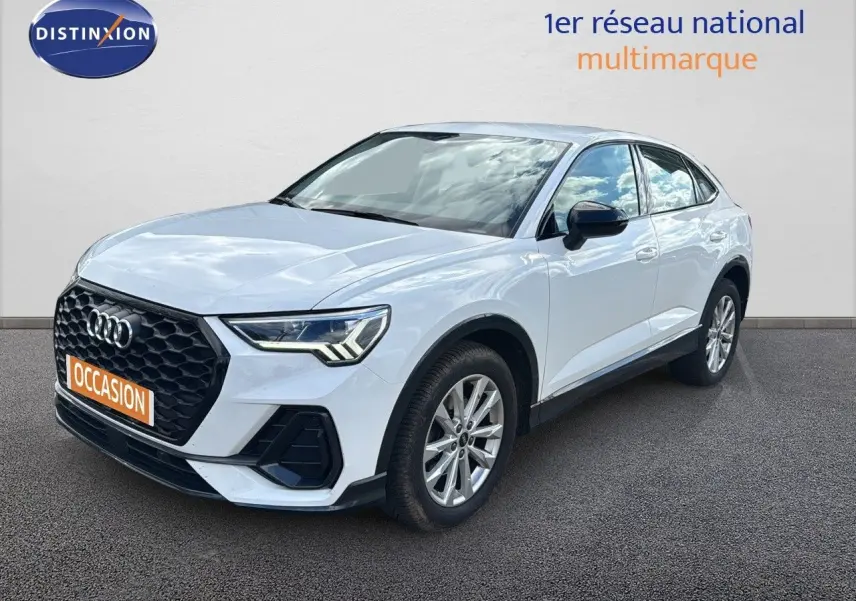 Audi Q3 Sportback blanc en 3/4 avant droit, avec calandre noire et feux LED distinctifs visibles.
