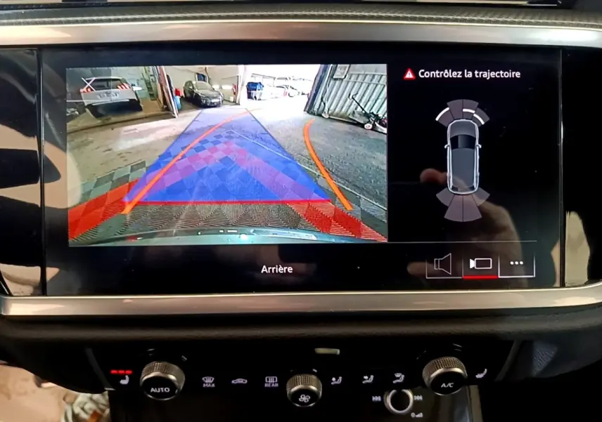Écran tactile intérieur montrant la caméra de recul et l'aide au stationnement du tableau de bord d'un Audi Q3 gris foncé.