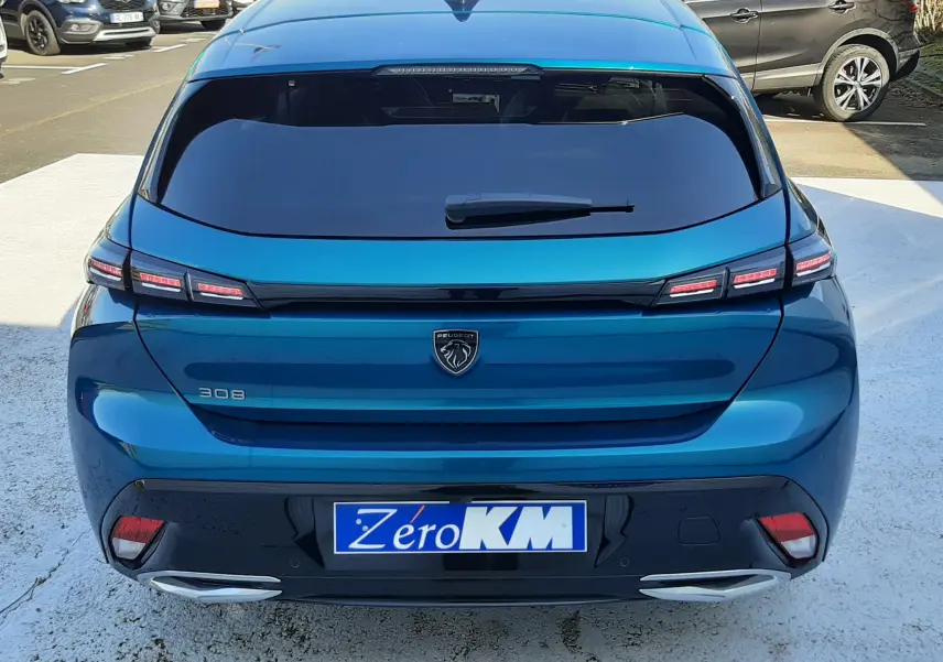 Vue 3/4 arrière droite d'une Peugeot 308 Bleu Obsession avec feux arrière distinctifs et jantes alliage bicolores.