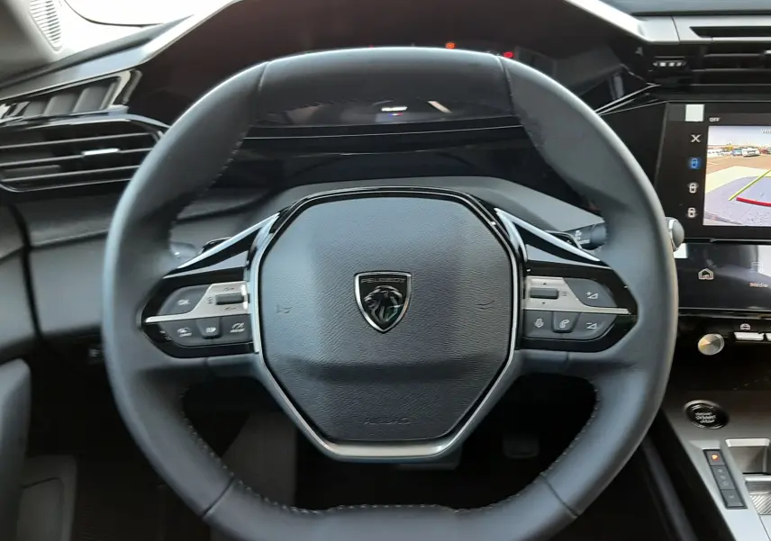Vue intérieure centrée sur le volant et la console centrale de la Peugeot 308 2026, avec écran tactile affichant la caméra 360°.