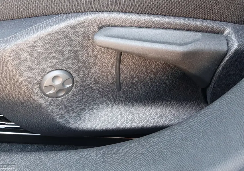 Gros plan sur le bouton de réglage électrique du siège avant, tissu noir avec surpiqûres blanches, intérieur Peugeot 308 Bleu Obsession.