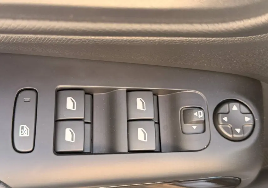 Gros plan sur les commandes de lève-vitres et réglages des rétroviseurs côté conducteur du Citroën C5 Aircross gris Platinium.