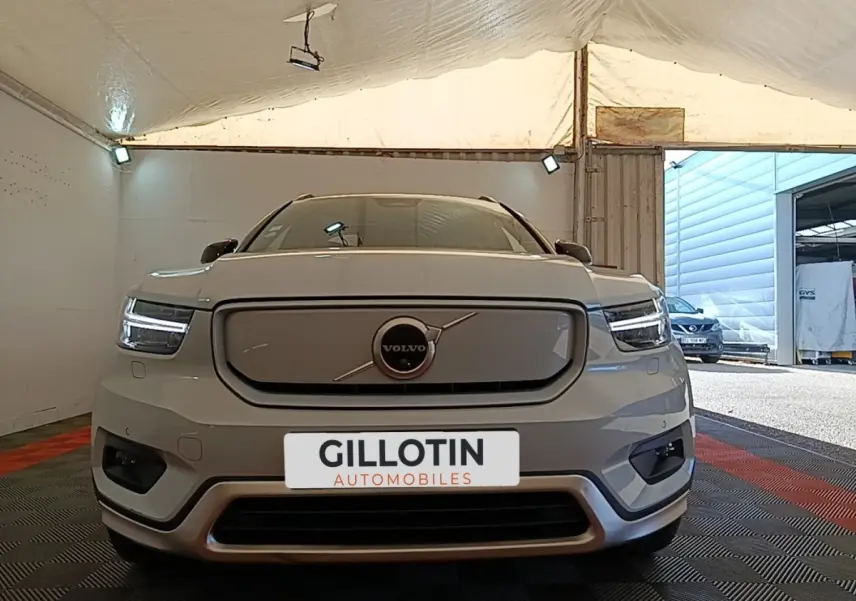 Vue frontale d'un Volvo XC40 P8 gris clair électrique avec phares LED et calandre fermée, en intérieur sous tente.
