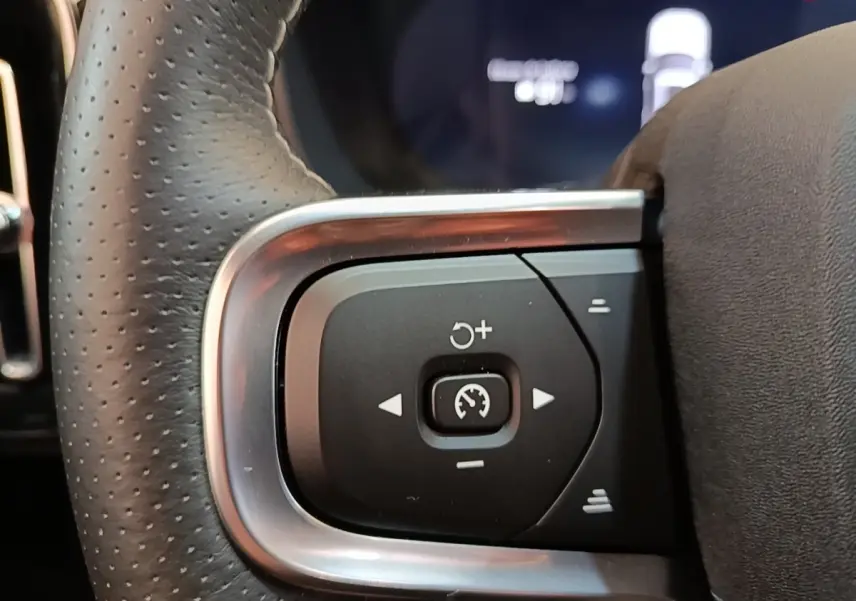 Gros plan sur les commandes de régulateur de vitesse au volant cuir perforé gris clair du Volvo XC40 électrique P8 R-Design.