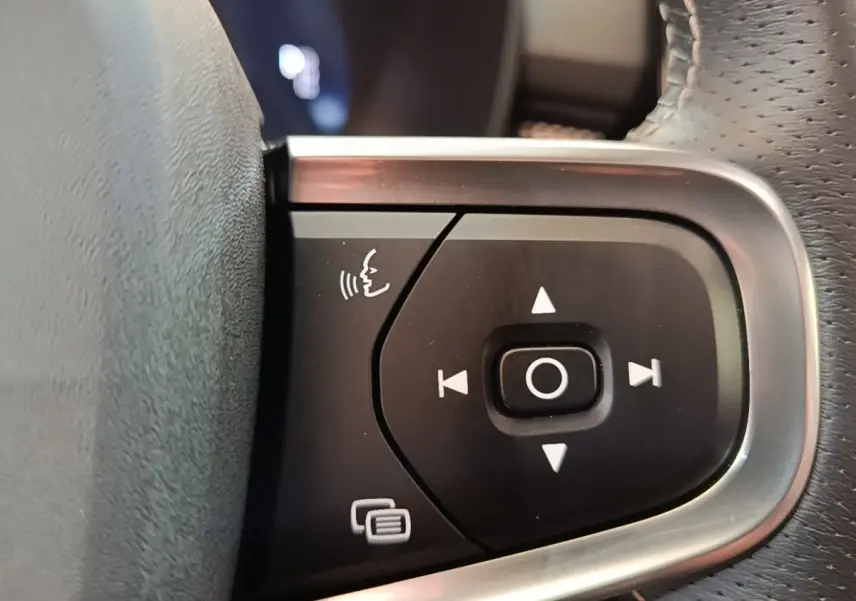Gros plan sur les commandes vocales et de navigation du volant cuir du Volvo XC40 gris clair, version P8 R-Design.