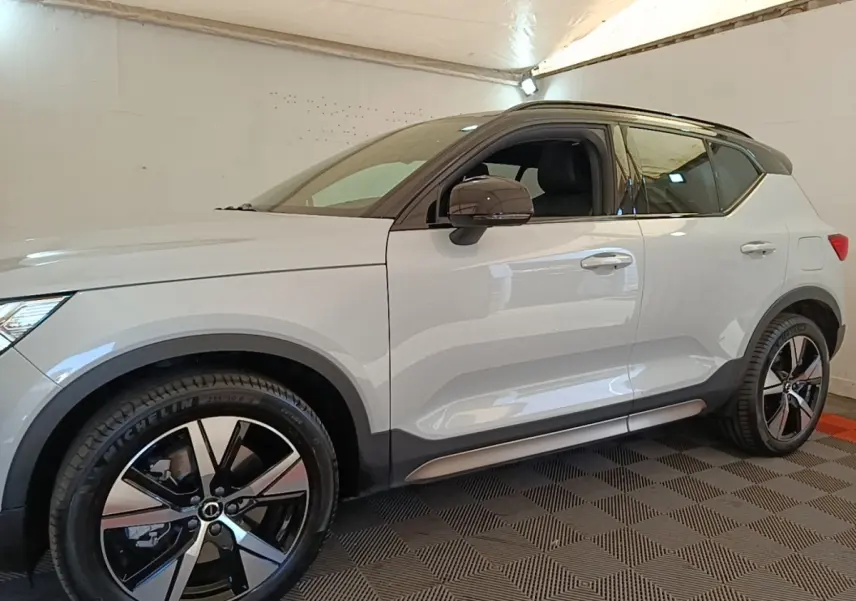 Vue de profil côté gauche d’un Volvo XC40 P8 R-Design gris clair avec jantes alliage noires et toit noir.