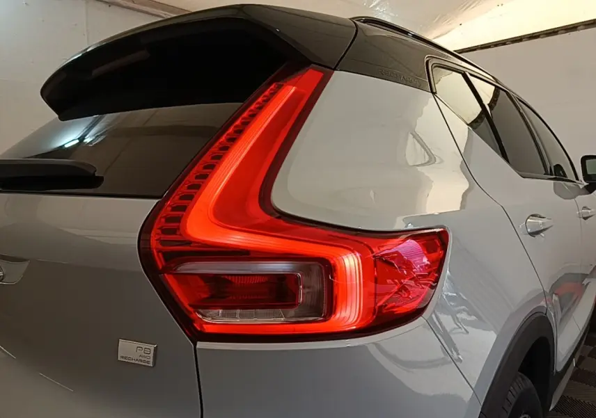 Vue 3/4 arrière droit du Volvo XC40 P8 gris clair avec feux arrière LED en forme de L et toit noir.