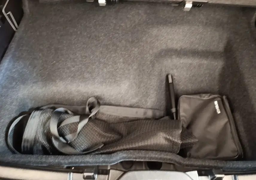 Coffre ouvert d’un Volvo XC40 gris clair, vue plongeante sur le rangement avec filet et sac noir.