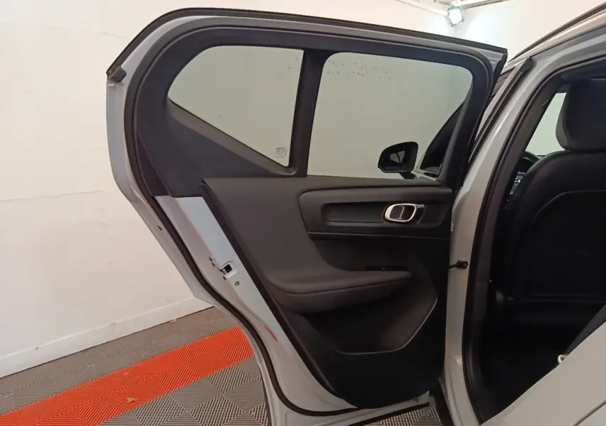Vue côté gauche arrière du Volvo XC40 P8 gris clair avec porte ouverte, montrant l'intérieur sobre de la porte arrière.