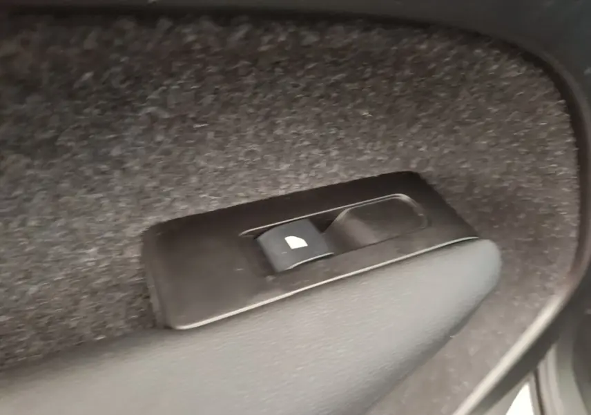 Gros plan sur l'interrupteur de verrouillage des vitres arrière dans un Volvo XC40 gris clair électrique.