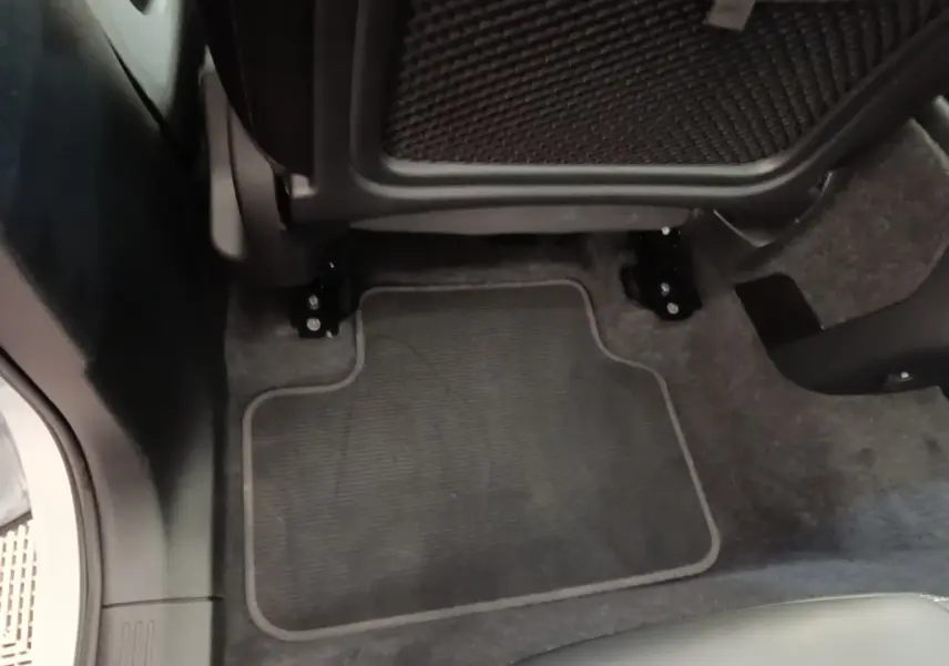Gros plan sur le tapis de sol gris foncé sous le siège arrière du Volvo XC40 P8 408 R-Design électrique.