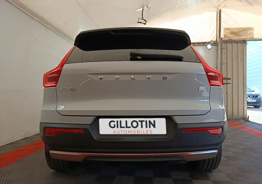 Vue arrière d'un Volvo XC40 gris clair électrique avec feux LED caractéristiques et logo centré sur le coffre.