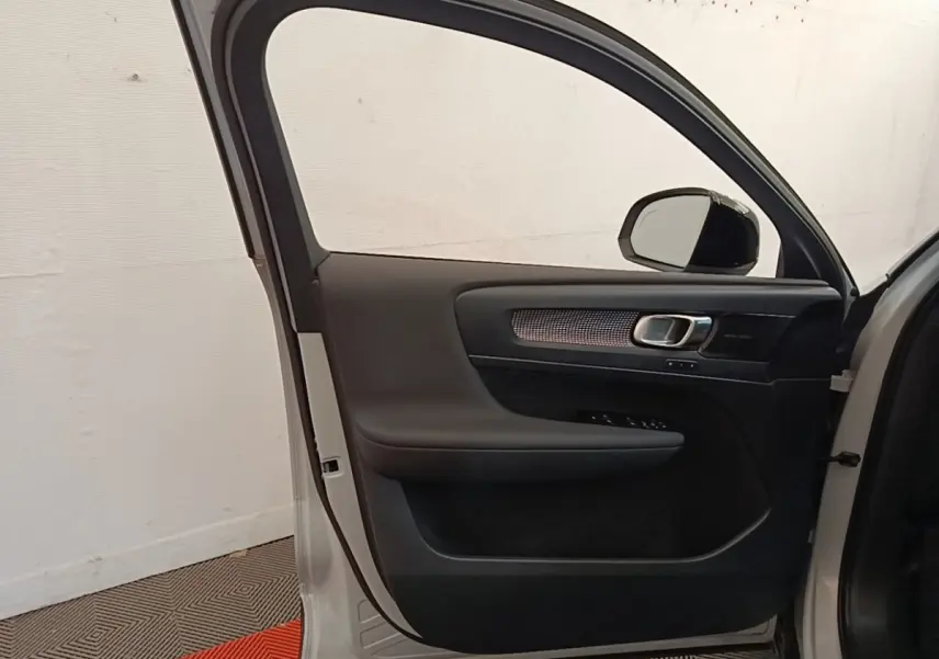 Vue intérieure de la porte avant gauche gris clair du Volvo XC40 P8 R-Design avec garniture noire et poignée métallique.
