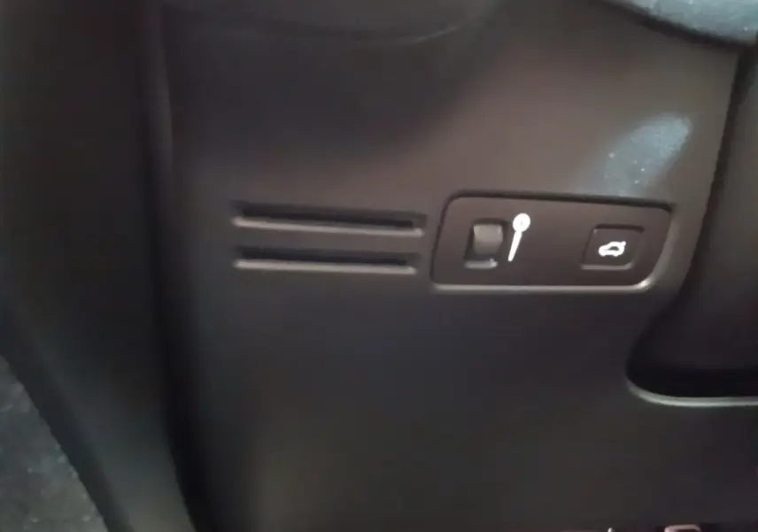 Détail intérieur noir du tableau de bord du Volvo XC40 P8 R-Design avec bouton ouverture coffre et levier de réglage.