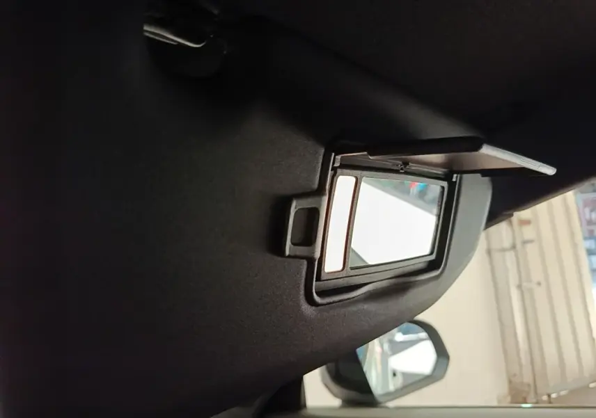 Miroir de courtoisie ouvert sur le pare-soleil côté conducteur dans l’habitacle gris du Volvo XC40 électrique.