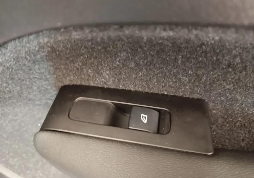 Gros plan sur le bouton de commande de lève-vitre électrique dans le coffre du Volvo XC40 P8 gris clair.