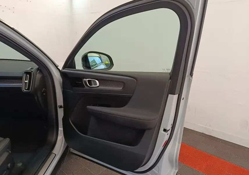 Vue intérieure de la porte avant gauche gris clair d’un Volvo XC40 P8 R-Design avec poignée alu et garniture noire.