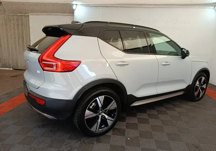 Vue 3/4 arrière droite d'un Volvo XC40 gris clair avec toit noir et feux arrière en forme de L lumineux.