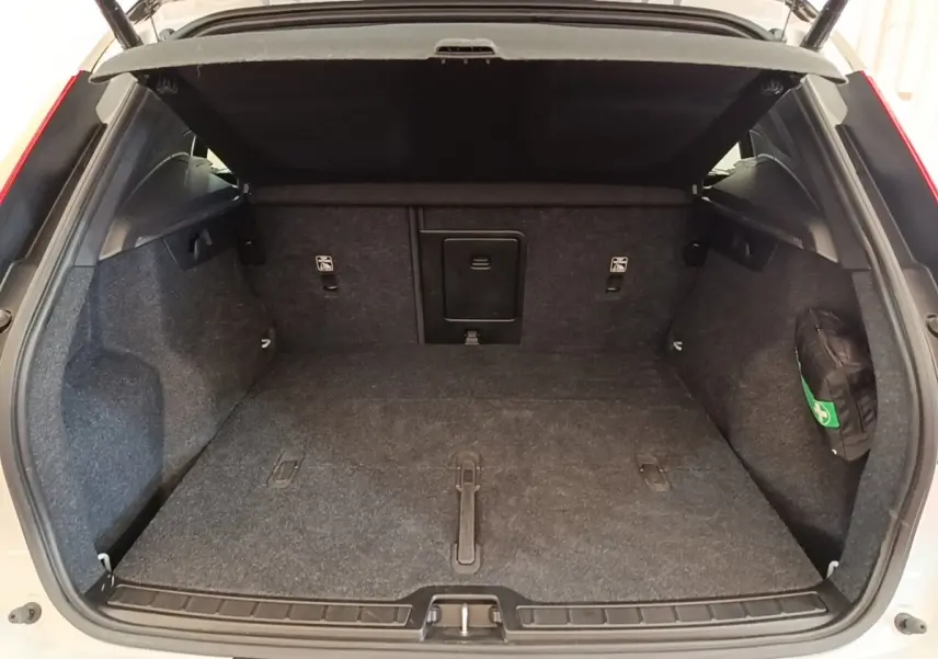 Coffre ouvert d’un Volvo XC40 gris clair, vue de l’arrière montrant un plancher plat et une banquette rabattable 2/3-1/3.