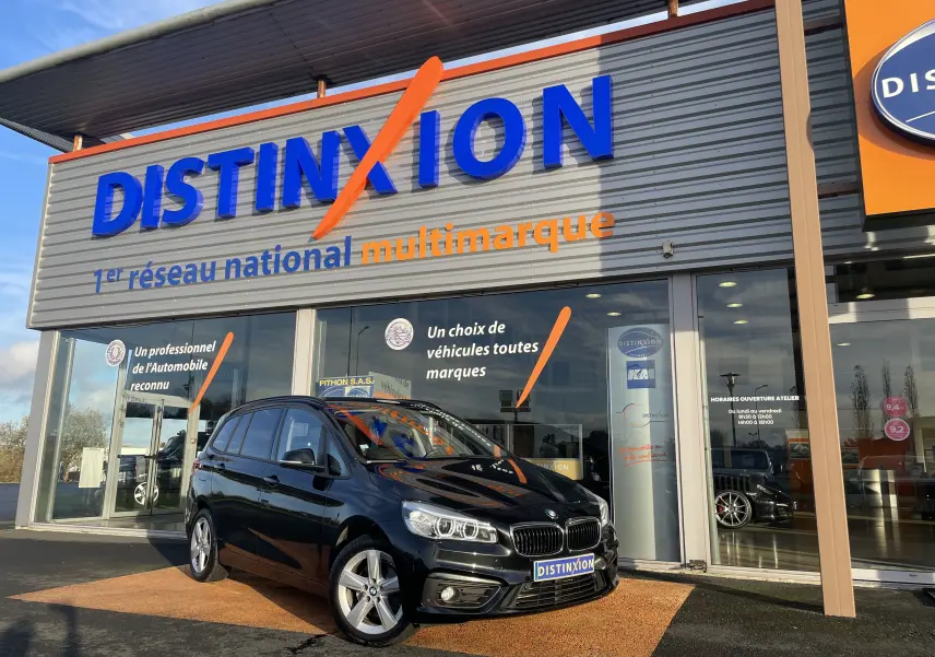 BMW Série 2 Gran Tourer noire vue en 3/4 avant droit devant un showroom Distinxion multimarque.