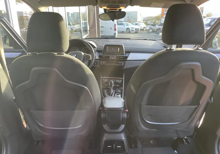 Vue intérieure arrière de la BMW Série 2 Gran Tourer noire, montrant les dossiers des sièges avant et le tableau de bord moderne.