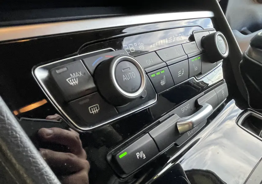 Gros plan sur la console centrale noire d'une BMW Série 2 Gran Tourer 218 DA 150 Lounge, avec commandes clim et mode sport.