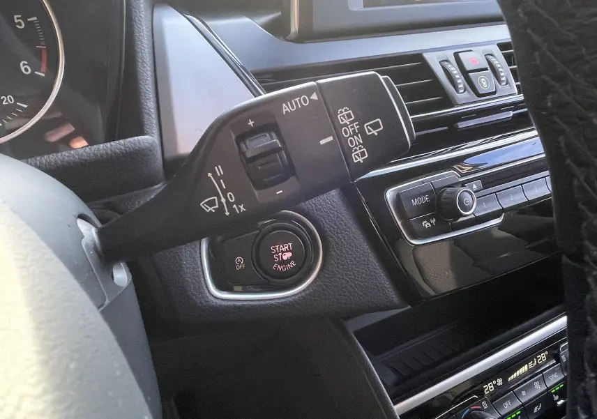 Détail du commodo d’essuie-glace et bouton start/stop sur le tableau de bord noir d’une BMW Série 2 Gran Tourer F46.