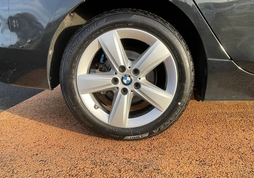 Gros plan sur la roue arrière droite d'une BMW Série 2 Gran Tourer noire, mettant en valeur la jante argentée et le pneu Bridgestone.