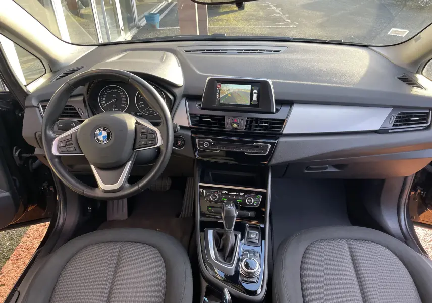 Vue intérieure avant du tableau de bord et volant noir de la BMW Série 2 Gran Tourer F46 avec écran central et console moderne.